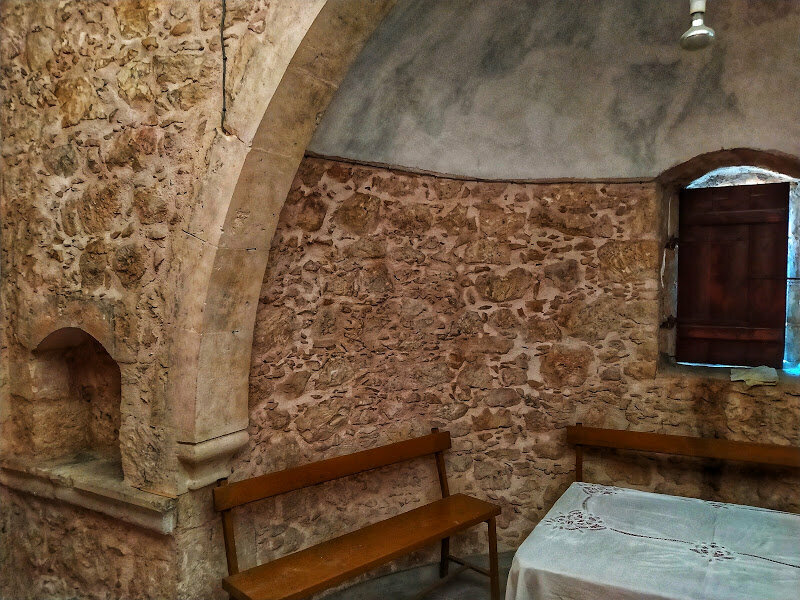 За алтарм. Скамейки стоящие вокруг стола в каменной церкви