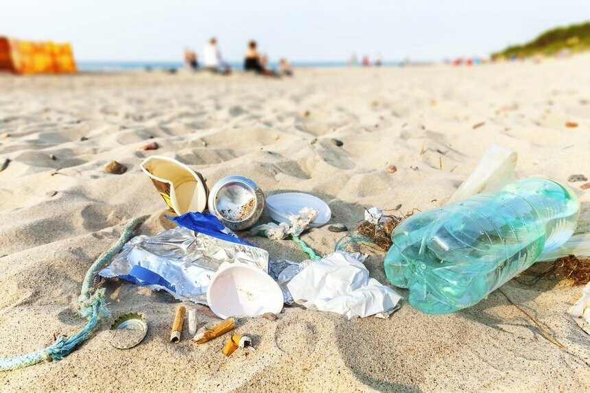 Пластиковые бутылки, окурки, мусор на пляже.
