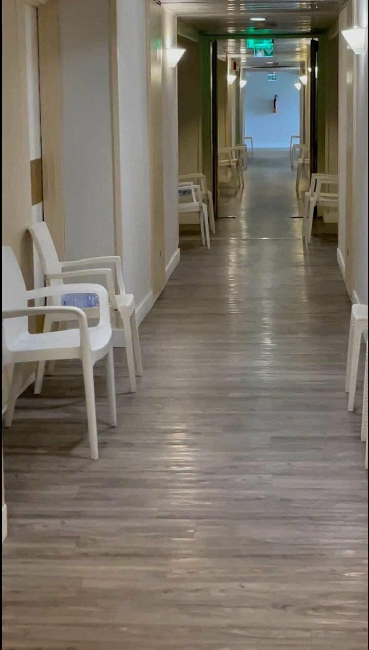 Пустой коридор отеля, застравленный стульями.