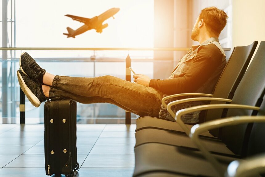 Мужчина сидит в аэропорту и наблюдает за отлётом самолёта - JESHOOTS-com