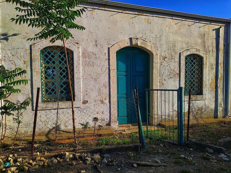 Дом с голубыми окнами и дверью в деревне Киос стоящий на вершине холма
