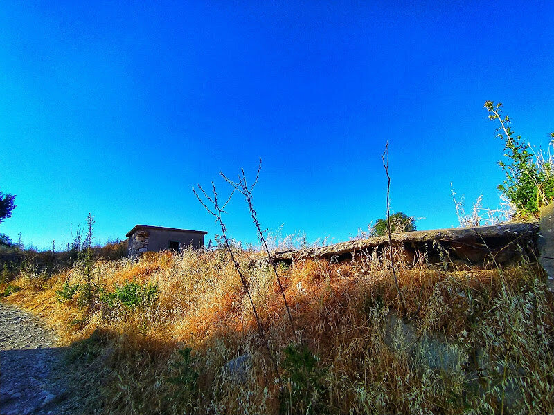 Разрушенный маленький дом стоящий рядом с дорогой в деревне Киос