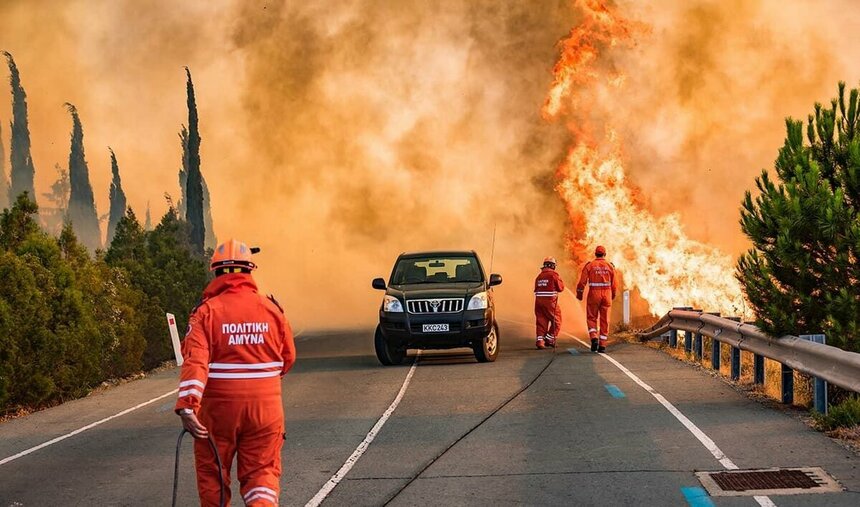 Пожарный бежит по дороге к бушующему пламени