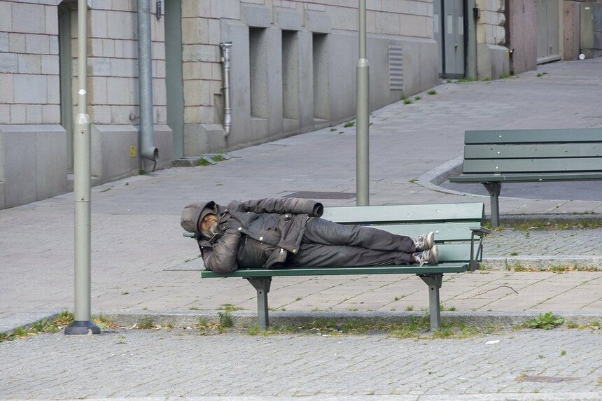 Бомж спит на лавке на безлюдной улице