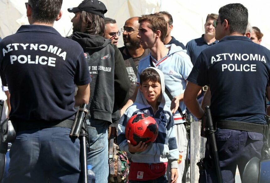 Несовершеннолетний мальчик-беженец в кругу полицейских на Кипре.