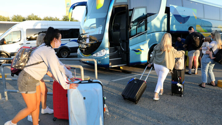 Туристы грузят чемоданы в автобус на Кипре.